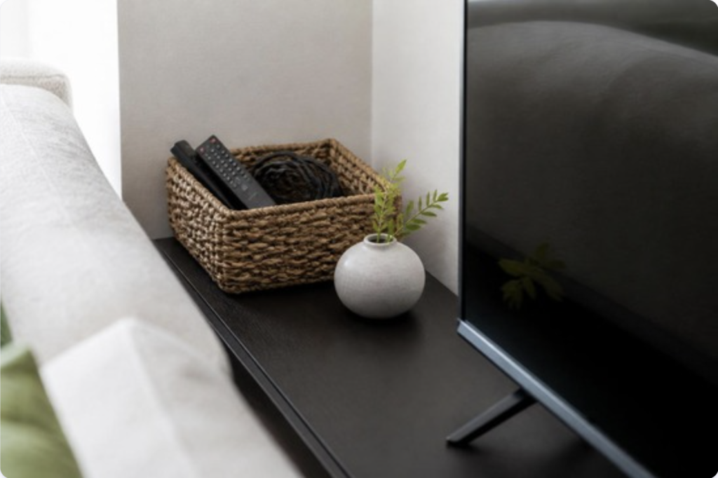 Tidy console table with a woven basket neatly holding remotes and cords tucked discreetly behind furniture