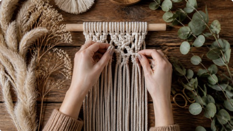 DIY home decor projects: hands tying a macrame knot surrounded by dried pampas grass and eucalyptus